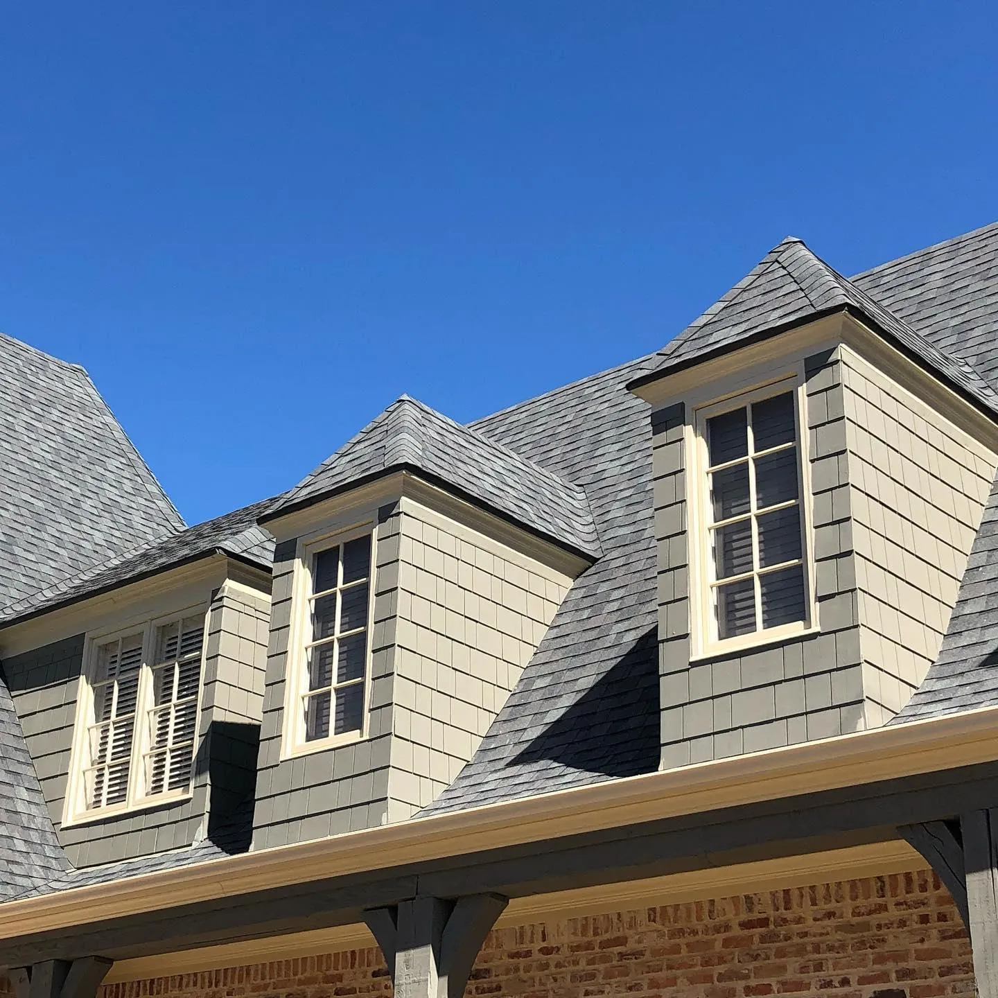 A brick house with a gray roof and white windows