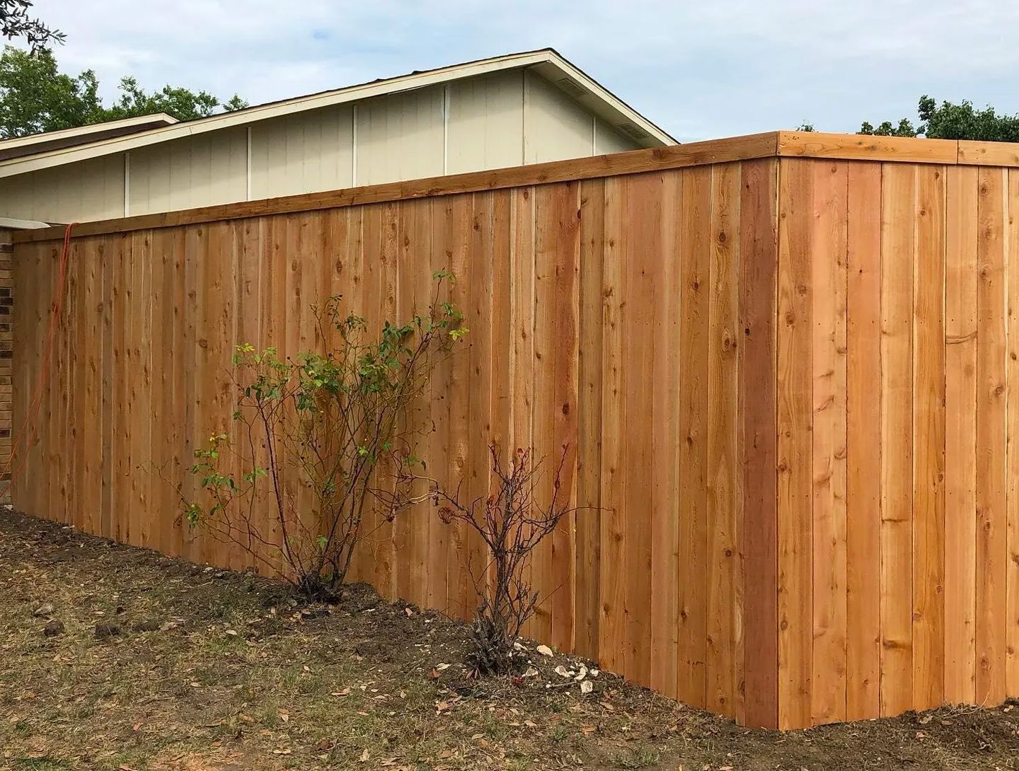 A wooden fence is sitting in front of a house.