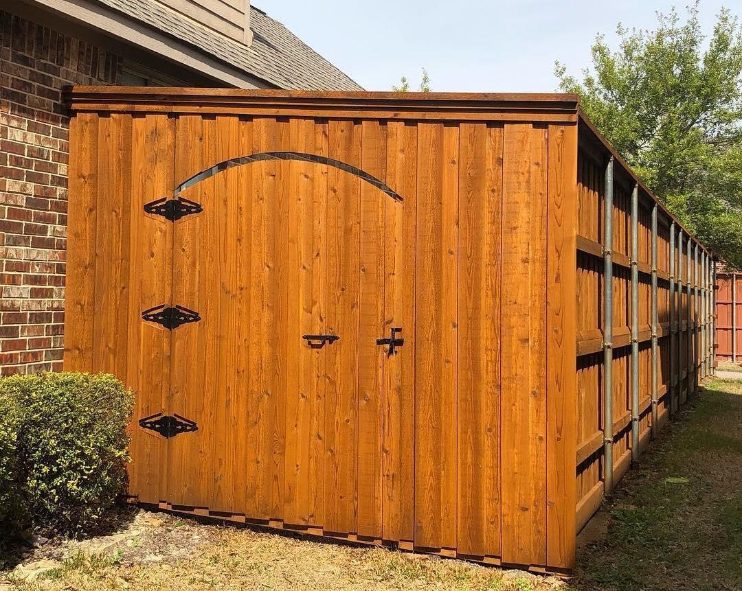 A wooden fence with a gate in the backyard of a house.