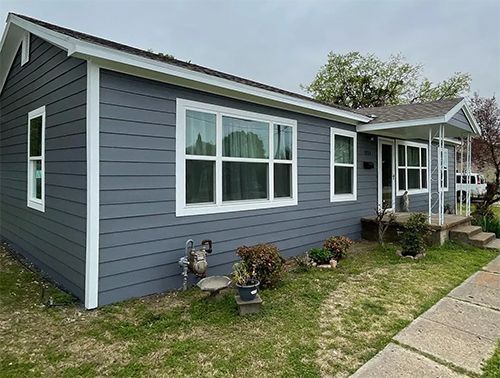 A small gray house with white trim and windows is for sale.