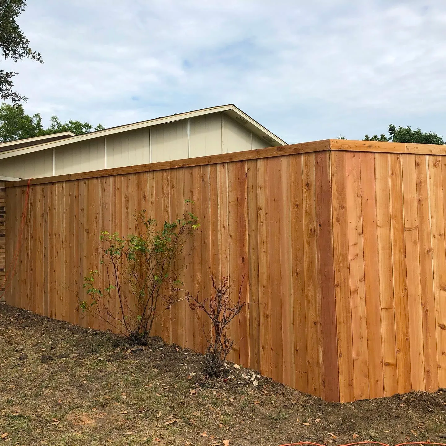 A wooden fence is in the backyard of a house.