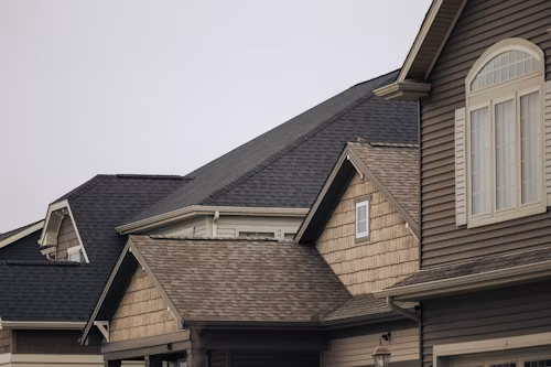 Suburban house roofs and beige siding under an overcast sky