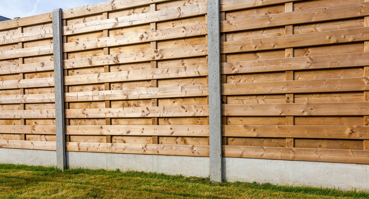 A wooden fence is sitting on top of a lush green lawn.
