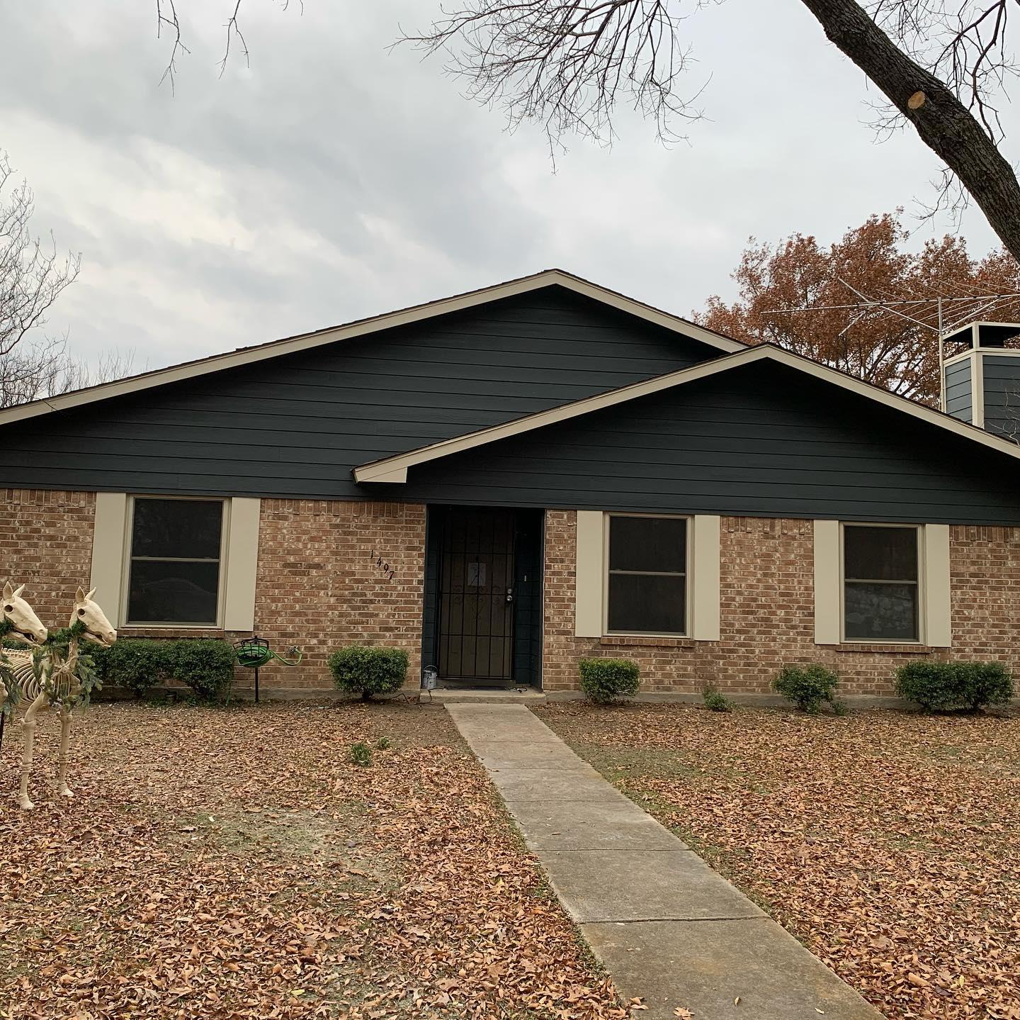 A brick house with a black roof and white trim