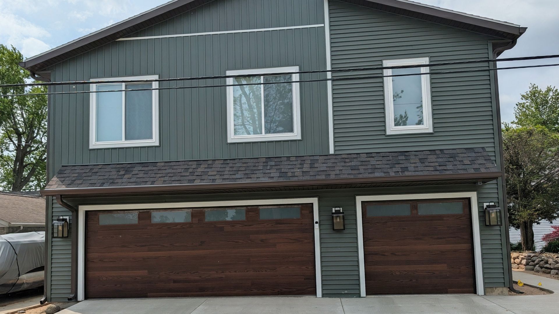 Two-story gray house with brown garage doors and white-trimmed windows