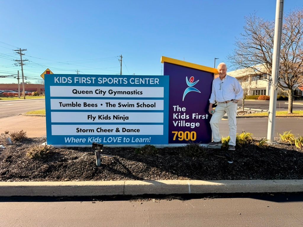Kids First Sports Center sign beside Jeff Metzger outdoors on a sunny day