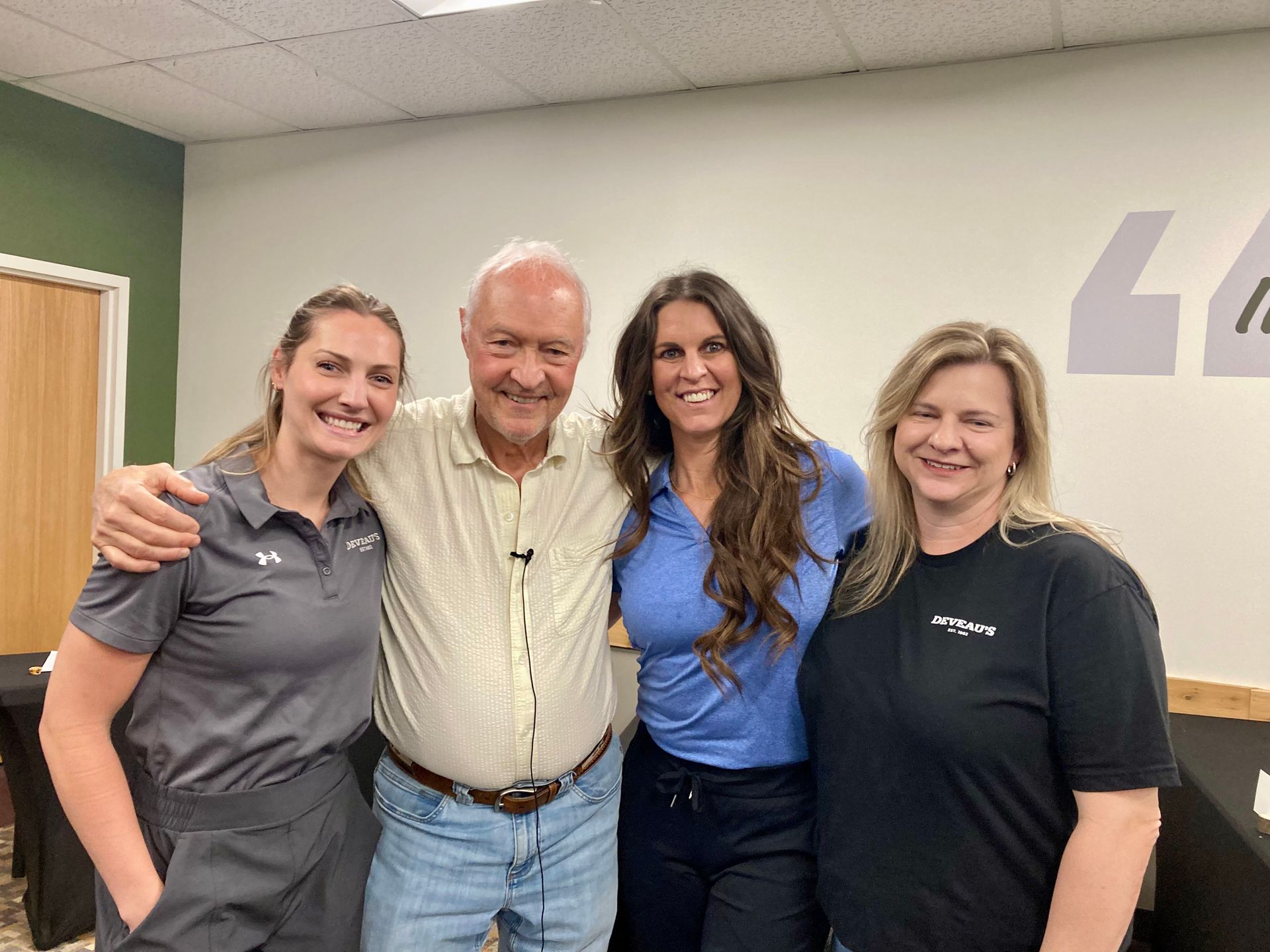 Three smiling people standing together with Jeff Metzger at a Boot Camp Session, with a green wall and wood door in the background.