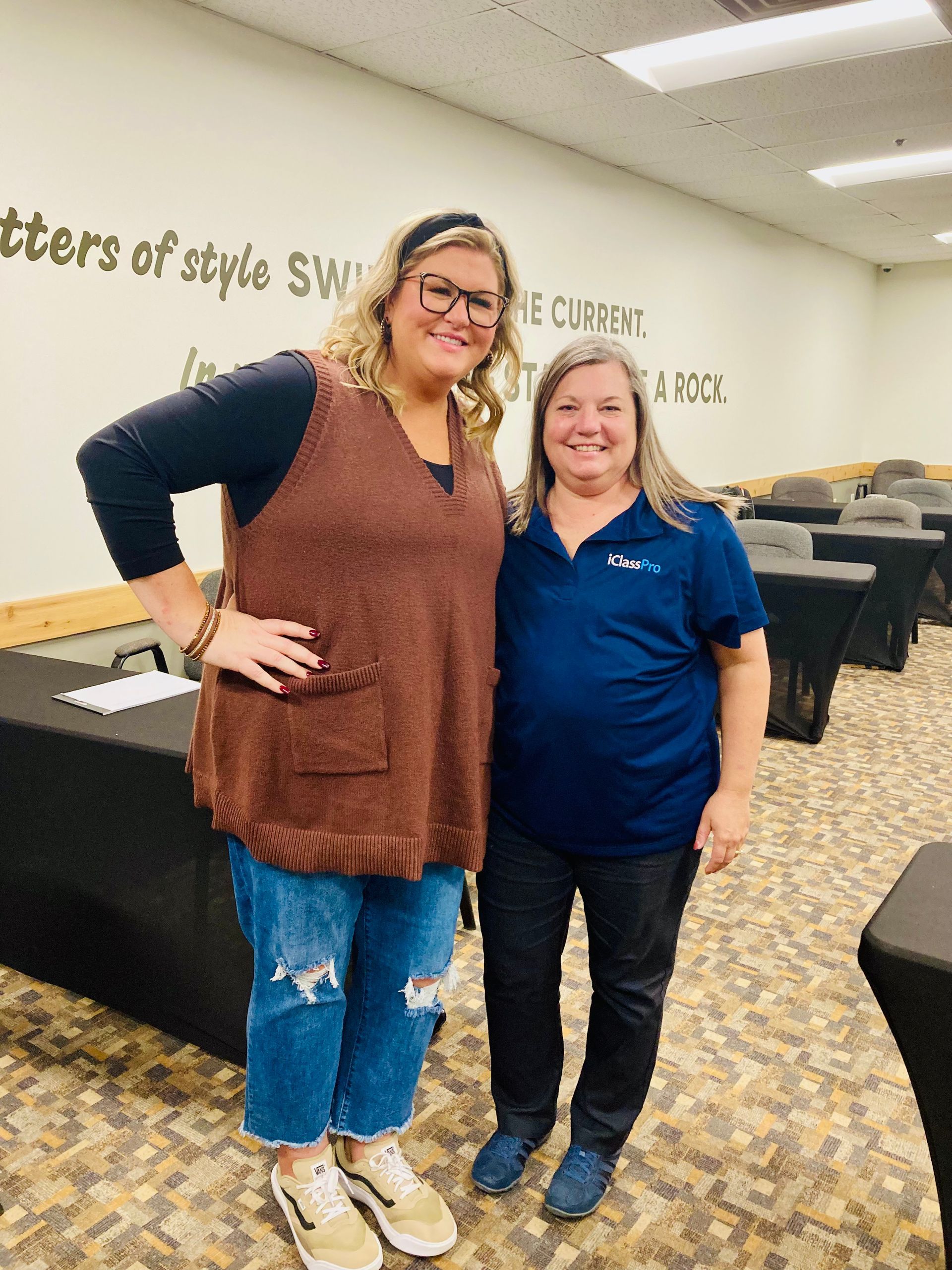 Megan Smith and Boot Camp attendee smiling in Boot Camp room, standing by desks and a wall with stylized writing.