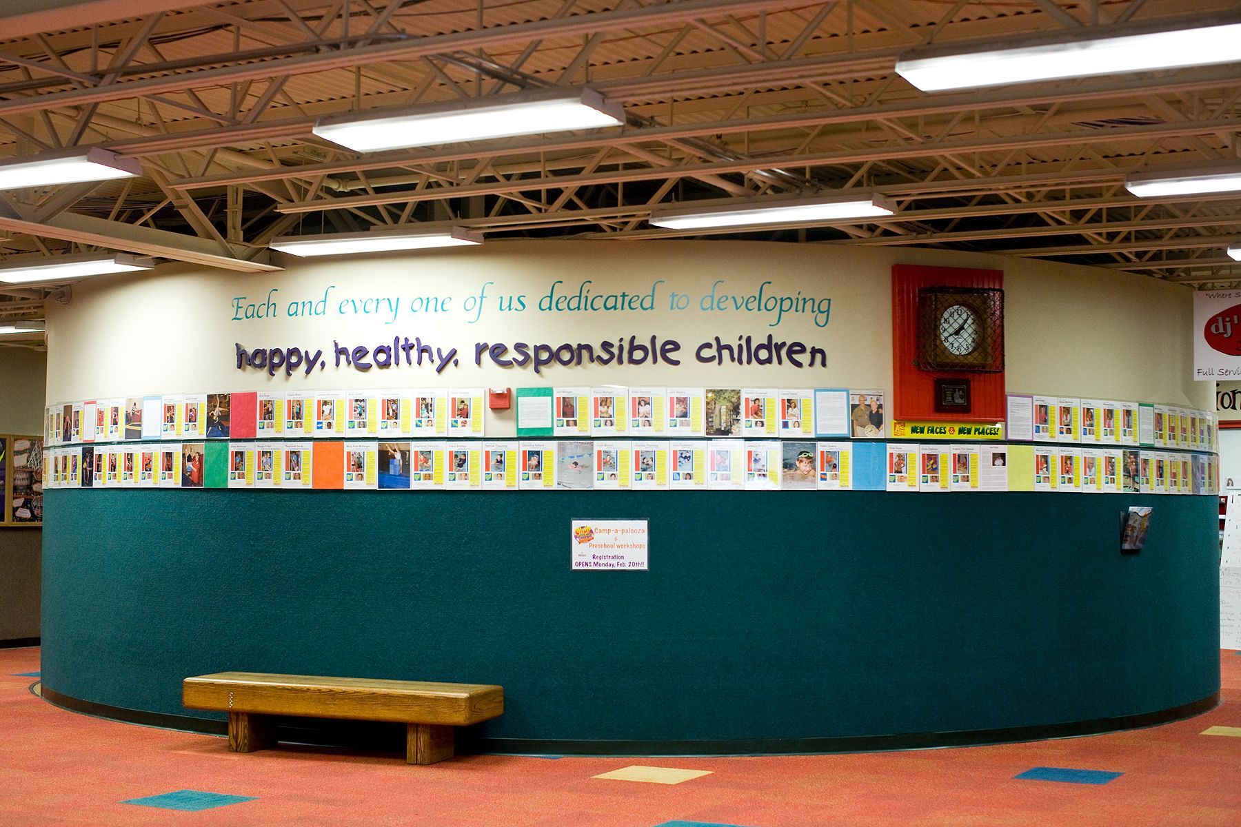 Library reading area with a teal circular counter, children’s books, and a “happy healthy responsible children” sign