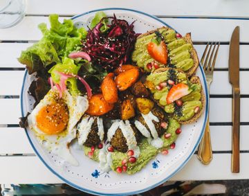 Colorful salad bowl with egg, avocado, greens, and pickled vegetables on a table with utensils