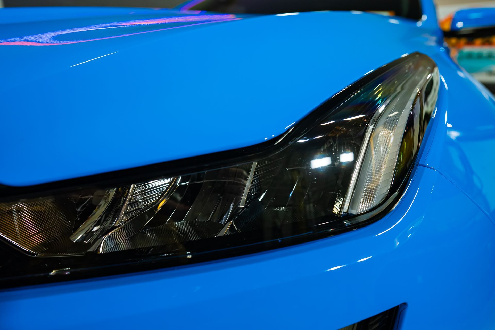 A close-up shot of a bright blue car's headlight with a sleek, modern design.