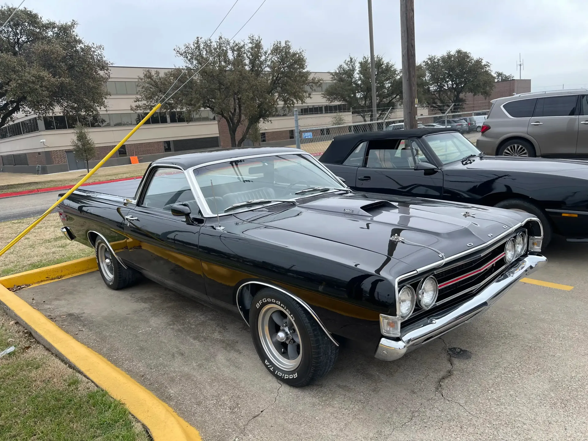 A glossy black vintage Chevrolet El Camino parked in a paved outdoor lot on an overcast day.