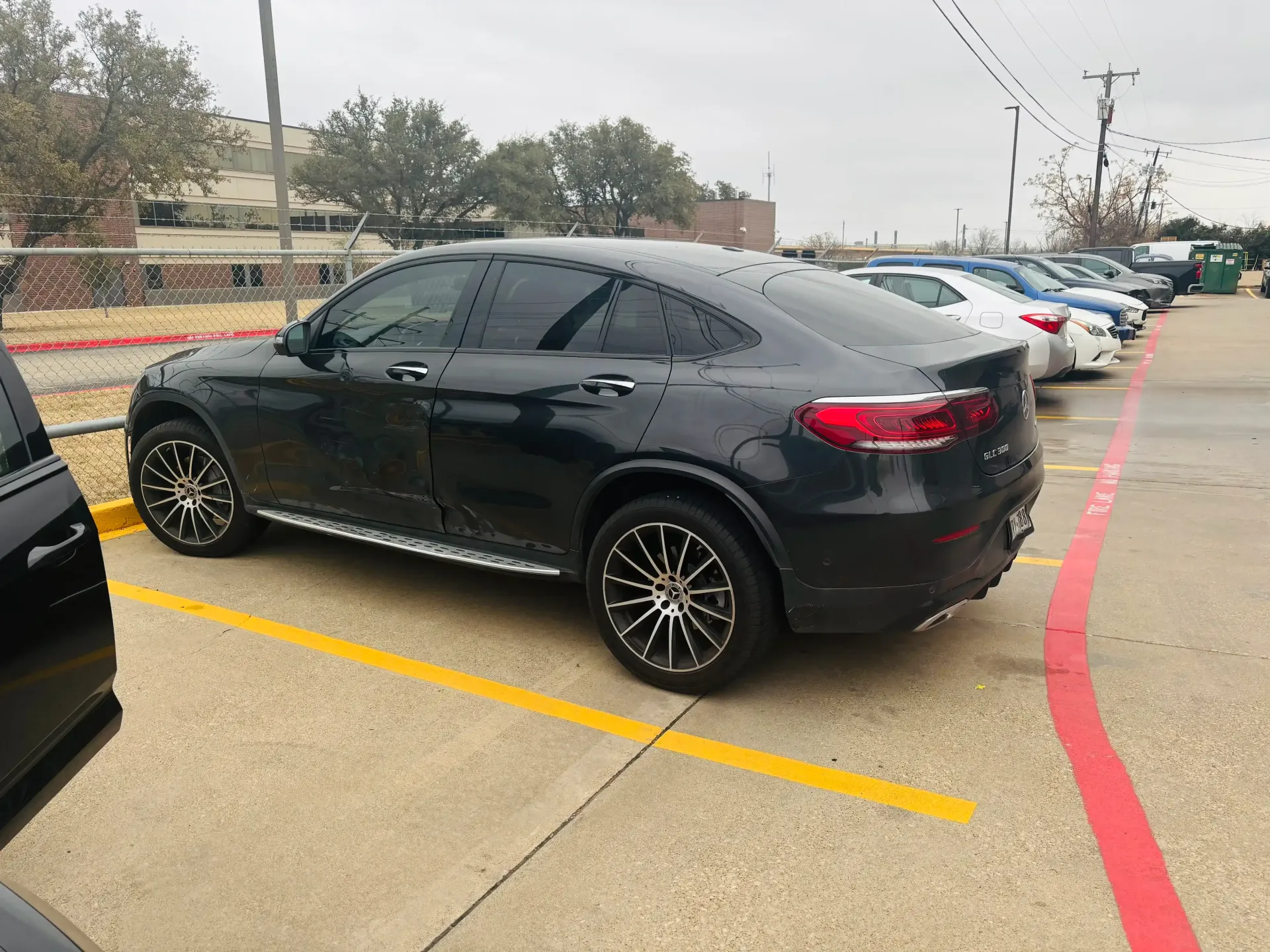 A dark-colored Mercedes-Benz GLC Coupe parked in a lot on a cloudy day.