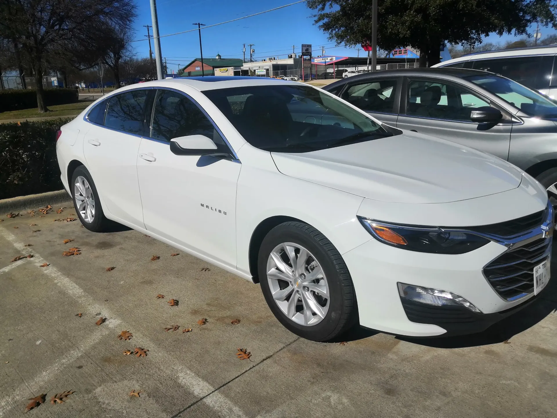 A white Chevrolet Malibu sedan parked in an outdoor lot on a sunny day.
