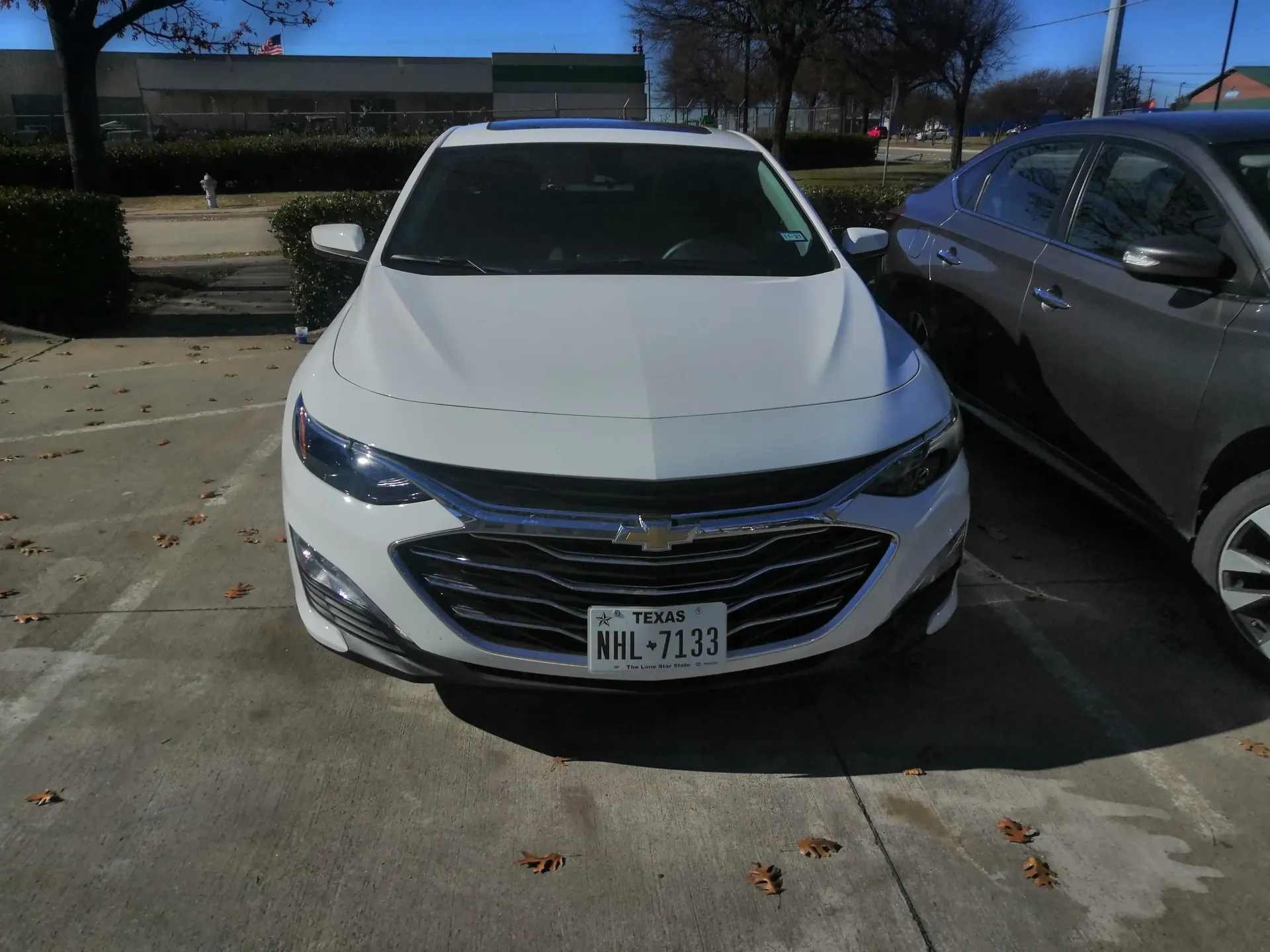 A white Chevrolet Malibu parked in an outdoor lot on a sunny day.
