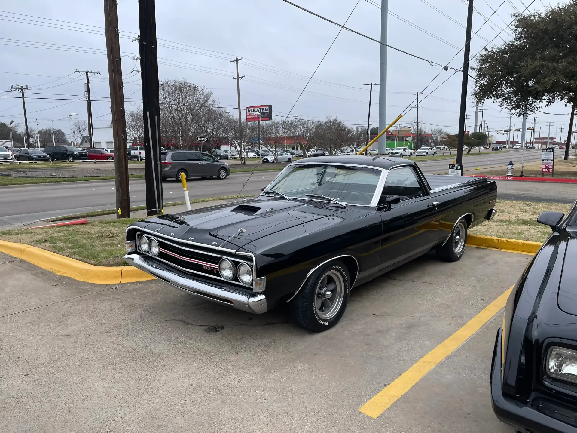 A black Ford Ranchero pickup truck parked in an outdoor lot on an overcast day.