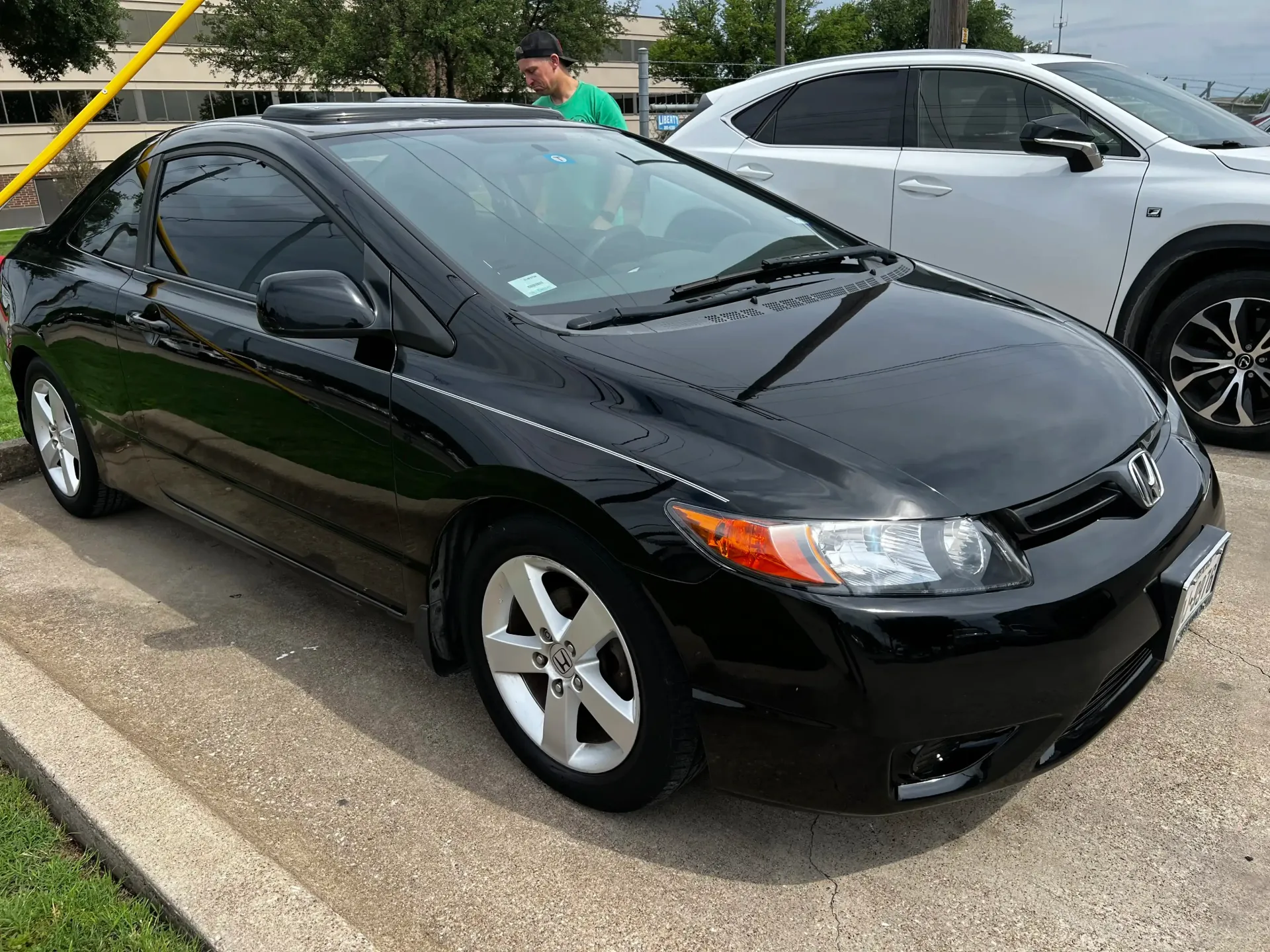 A shiny black two-door Honda Civic coupe parked in a lot, viewed from the front passenger side.
