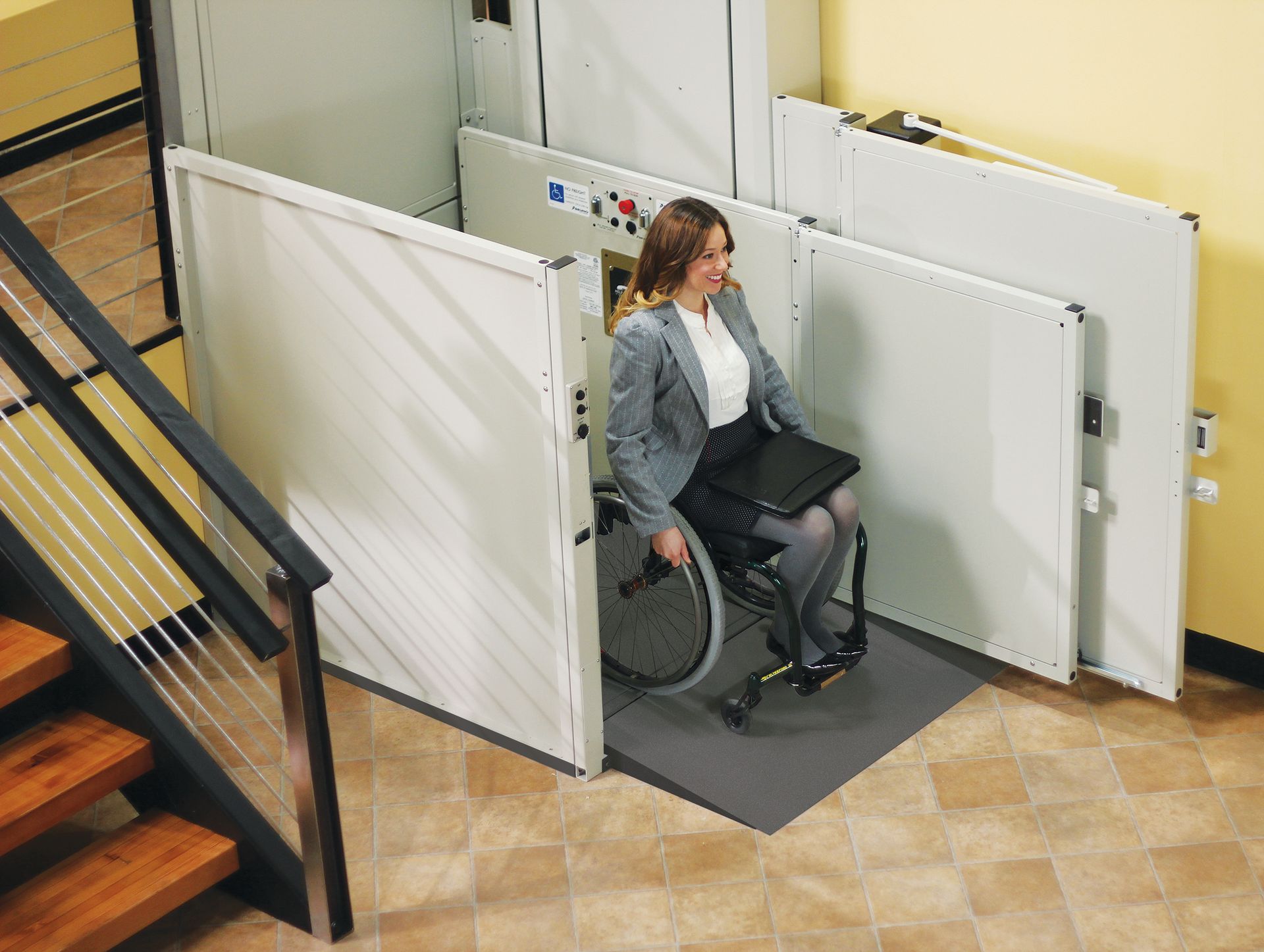 Wheelchair user exiting a vertical platform lift onto a home's porch landing