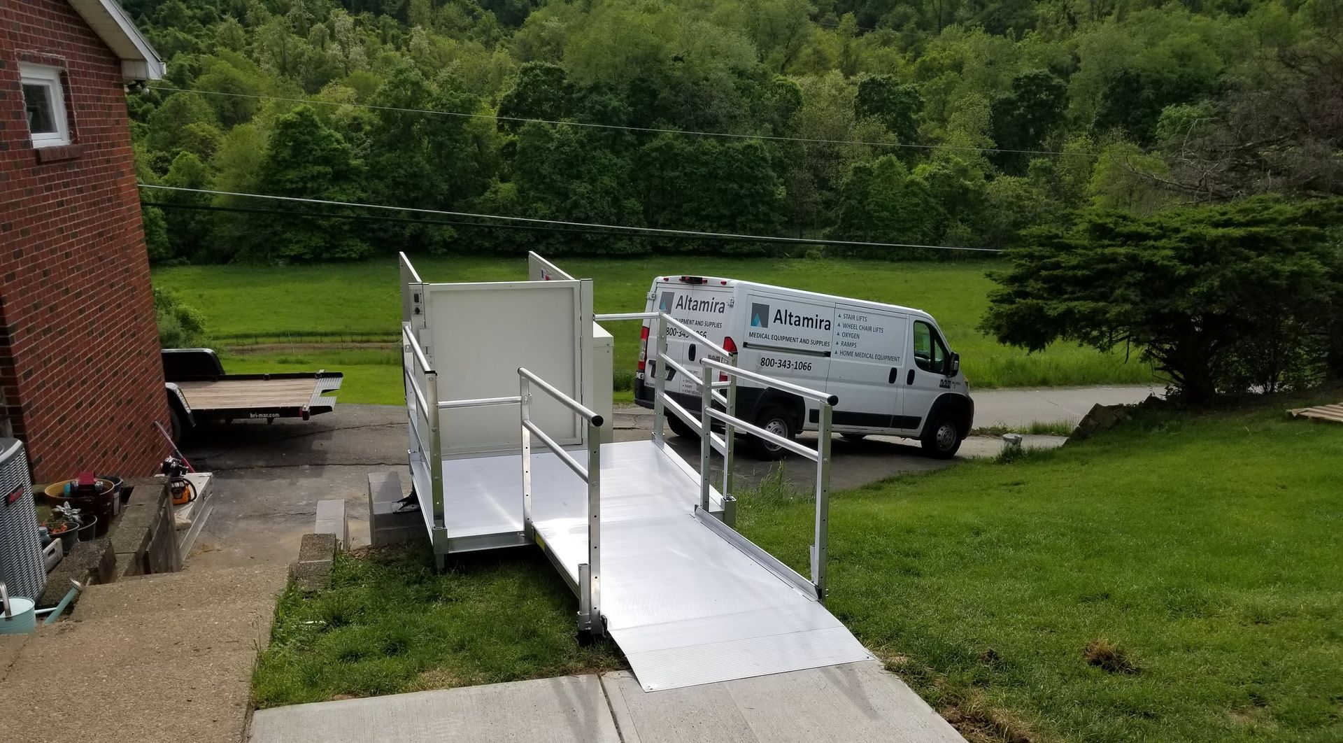 A white van is parked next to a ramp in front of a brick house