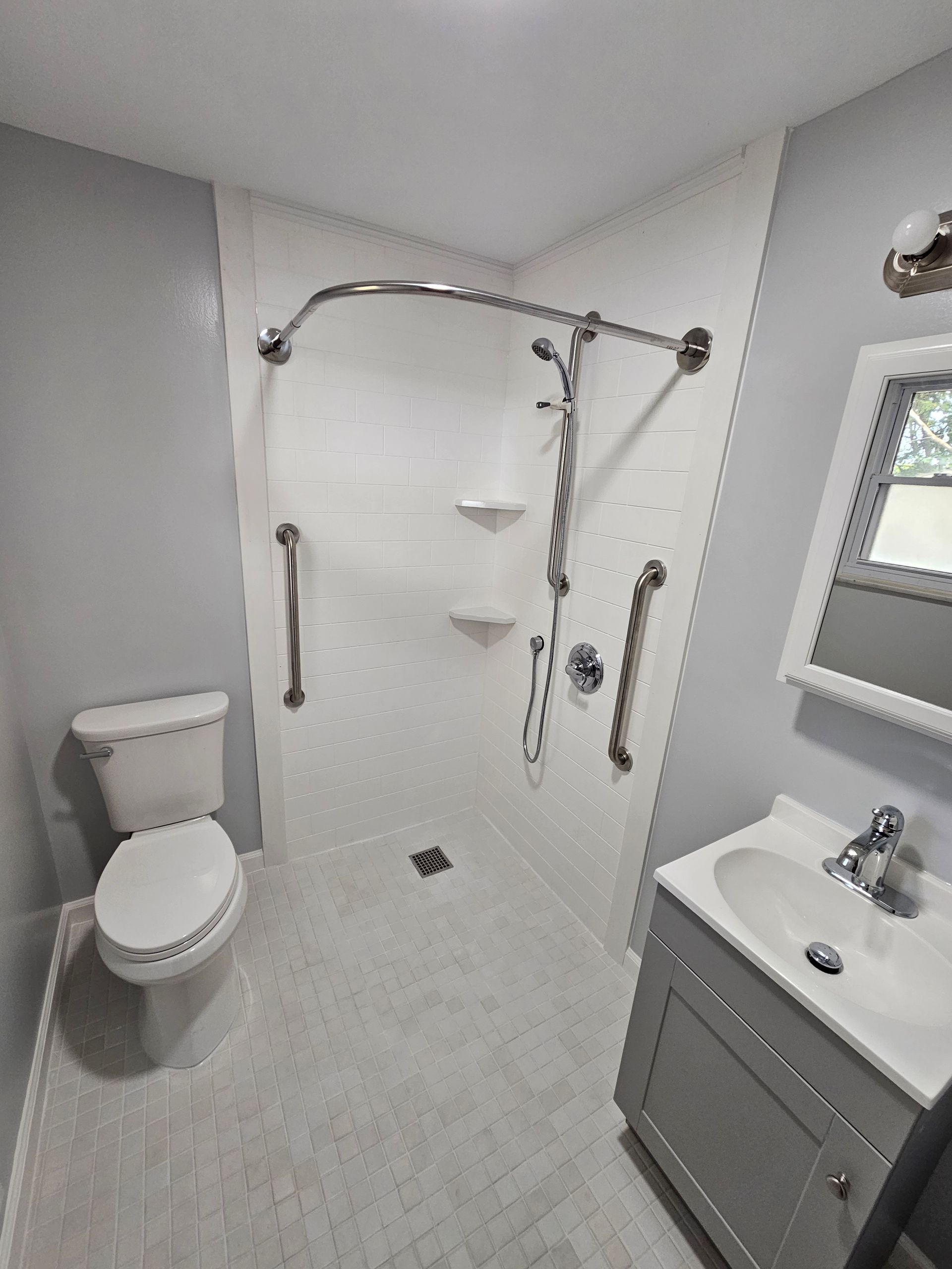 An accessible bathroom modification by Altamira Ltd. with a toilet , sink and shower.