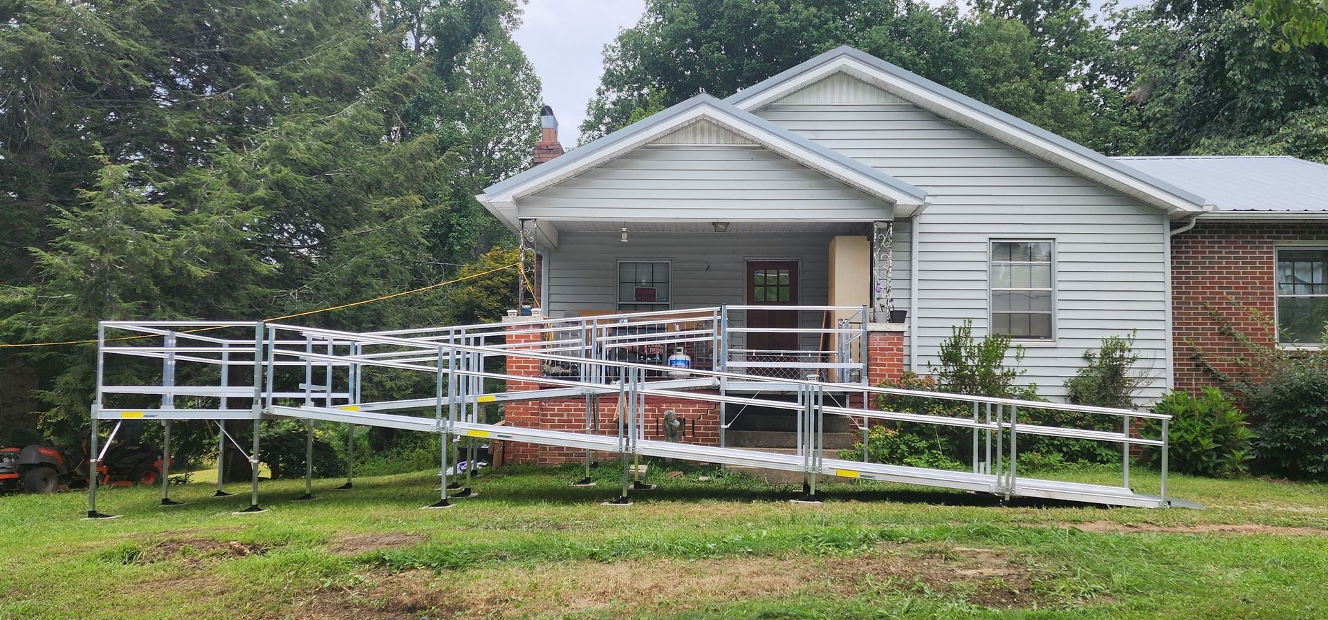 A professionally installed modular wheelchair ramp with handrails and a turn platform leading to a home's front entrance