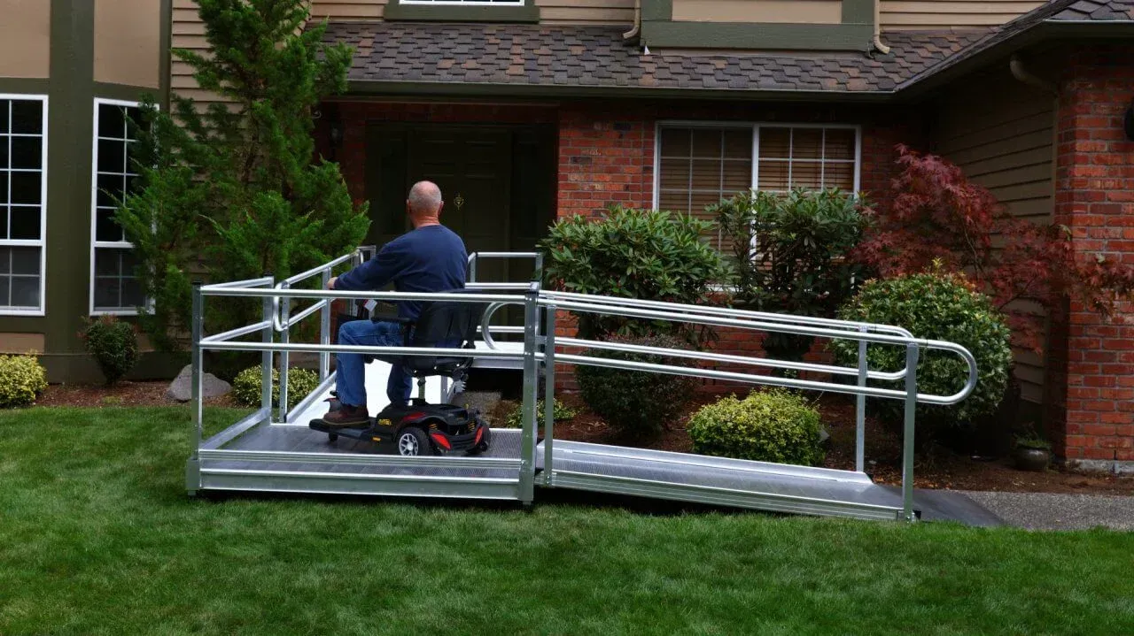 A man in a wheelchair on a ramp in front of a house