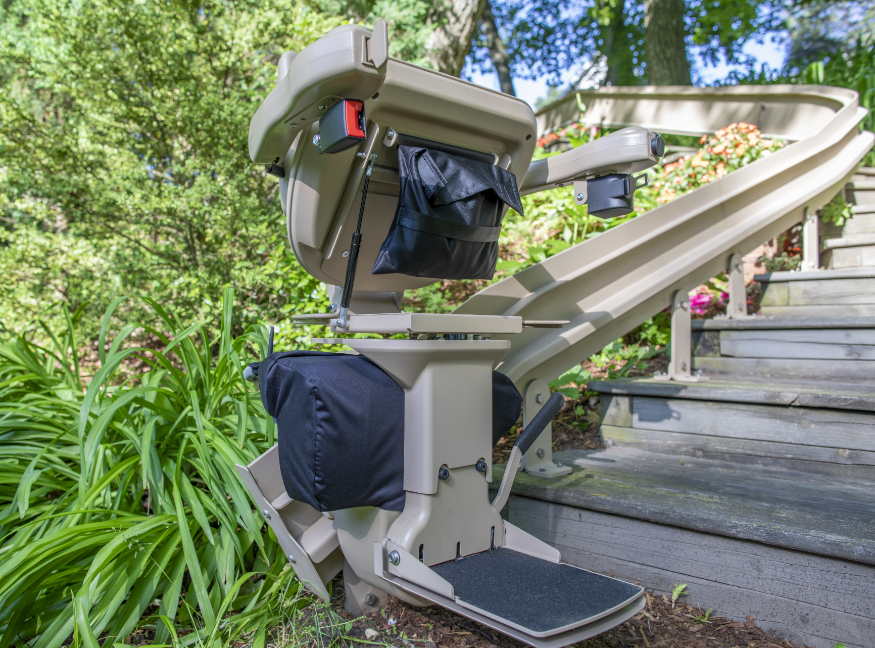 An outdoor curved stair lift sitting on the side of a set of stairs.