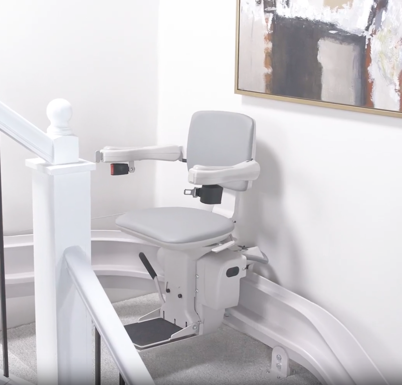 A white stairlift with a picture on the wall above it, installed by Altamira Ltd.