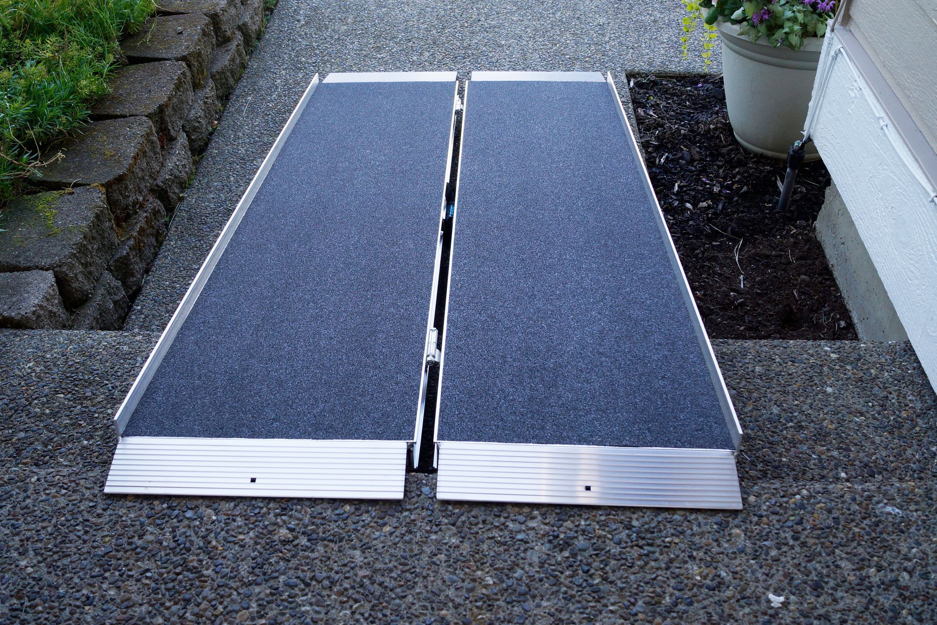 A portable ramp on a sidewalk next to a potted plant