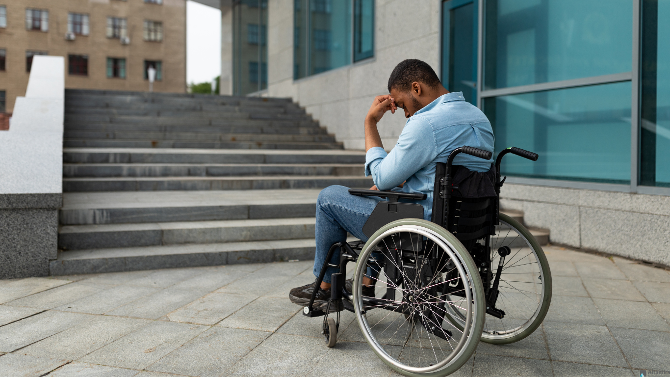 A man in a wheelchair is sitting in front of stairs.