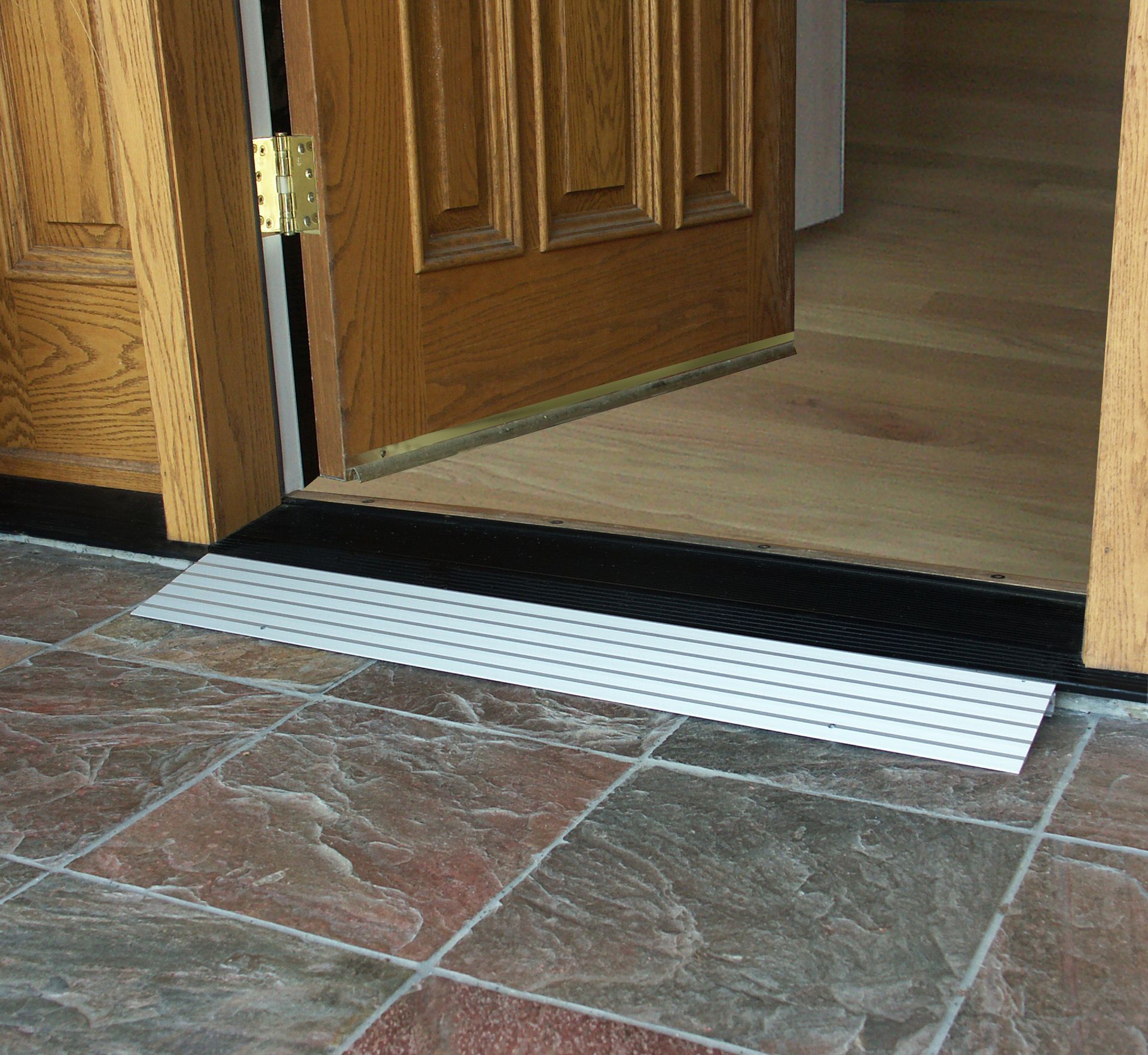 A wooden door with a metal transition ramp in front of it