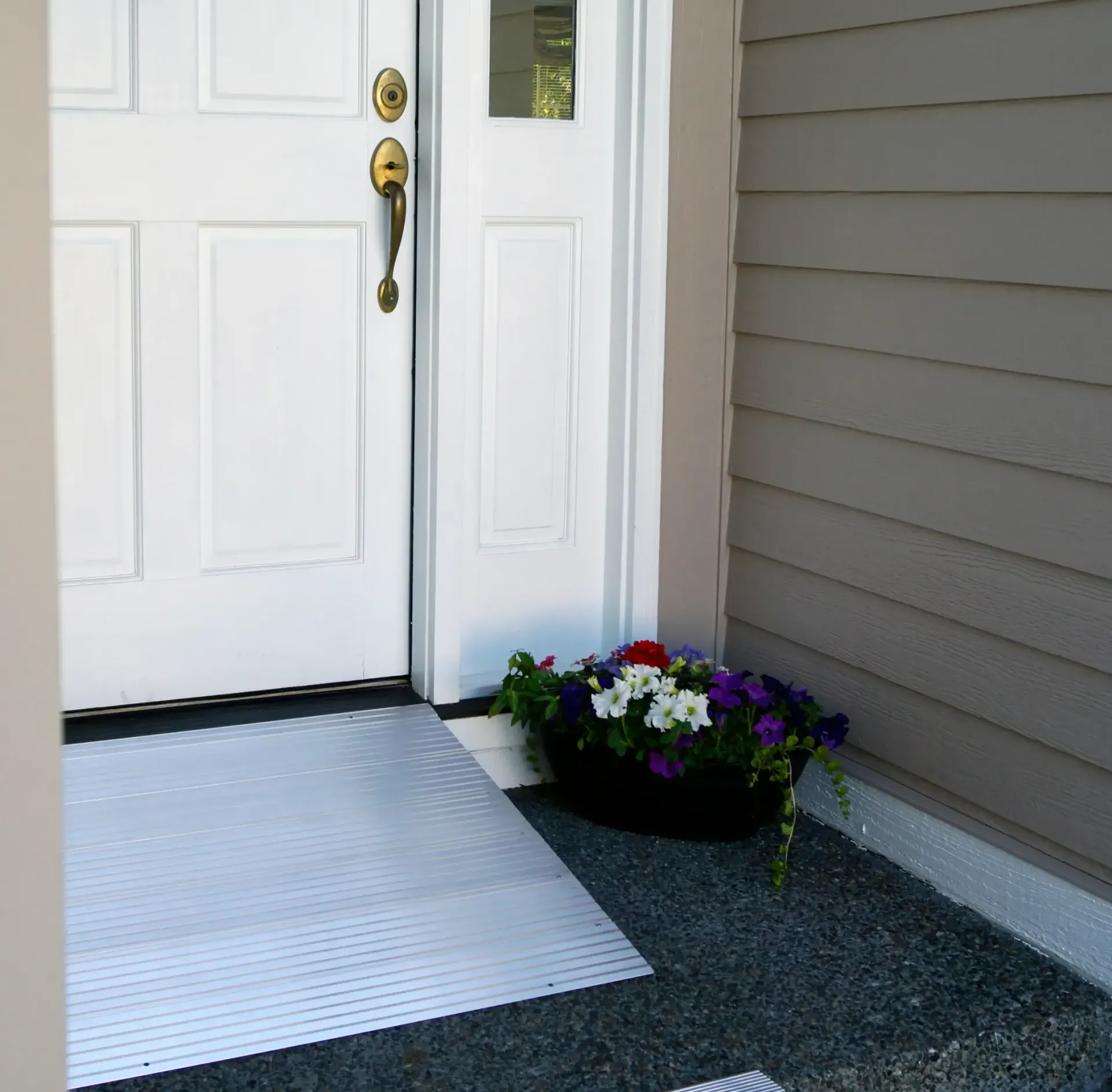 White door with metal ramp for accessibility and a flowerpot.