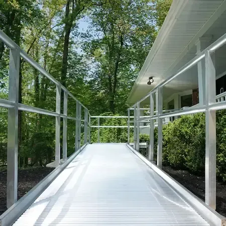 Aluminum modular wheelchair ramp with handrails leading up to a home's front entrance