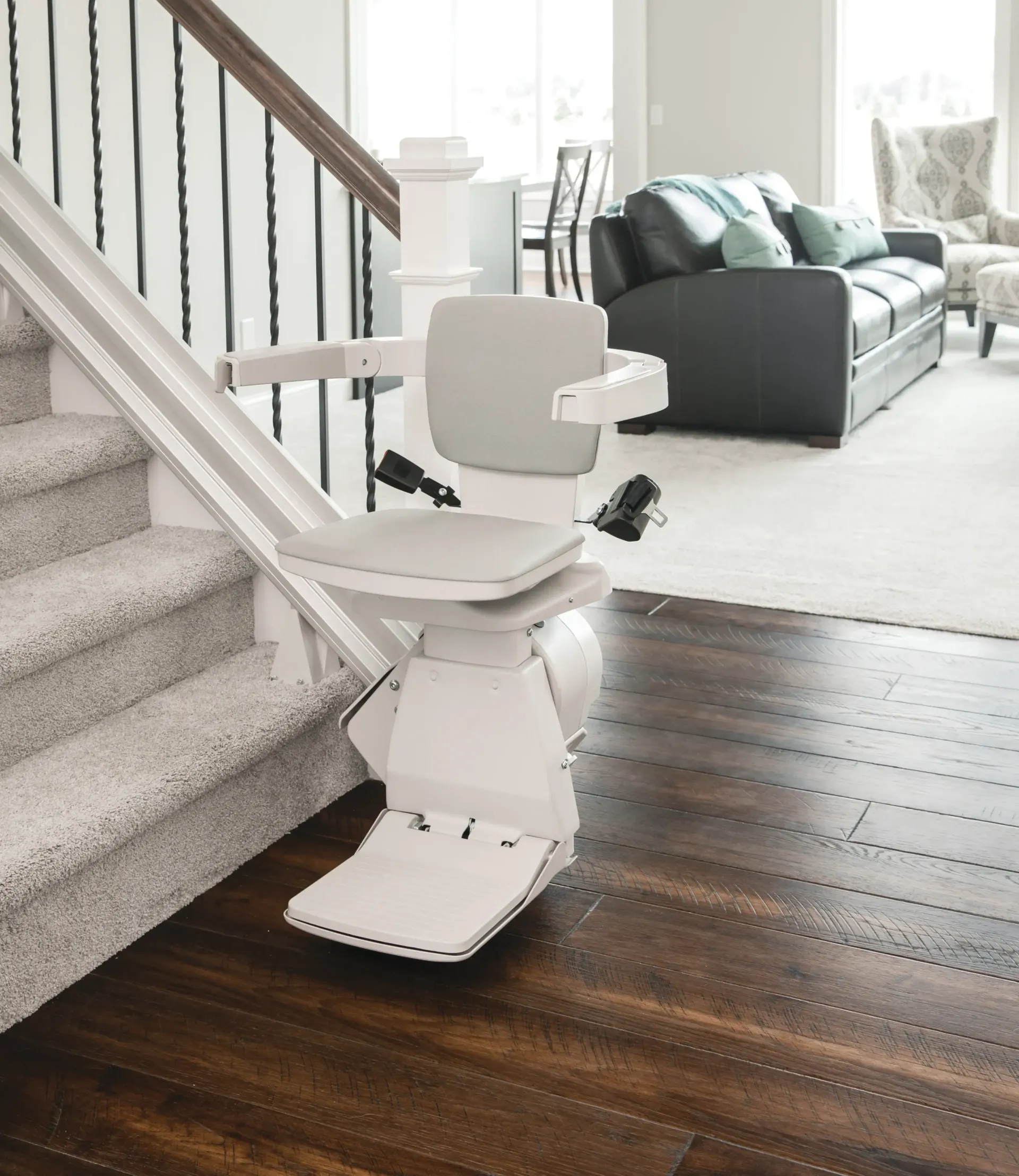 A stair lift made by Bruno and installed by Altamira Ltd. New Jersey in a living room next to a couch.