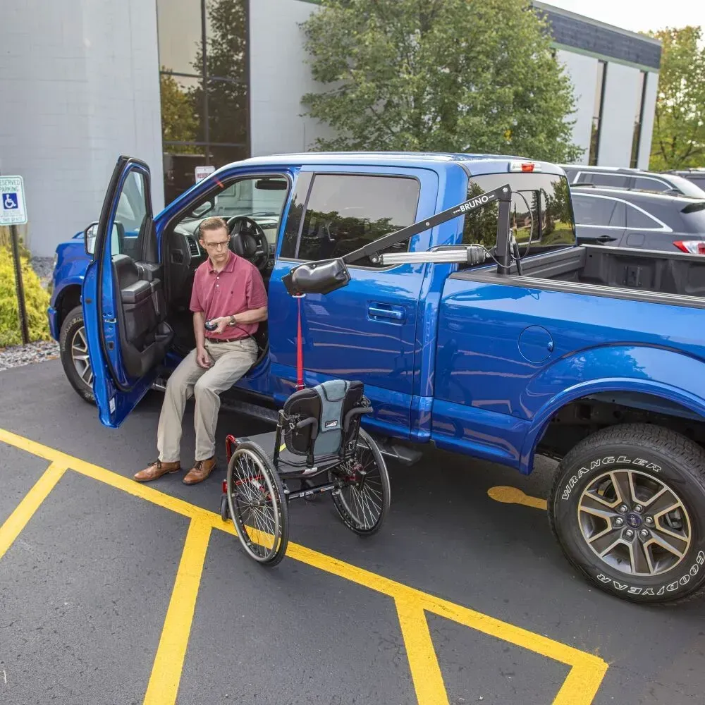 A Bruno Out-Rider pickup truck bed vehicle lift lowering a wheelchair to the ground