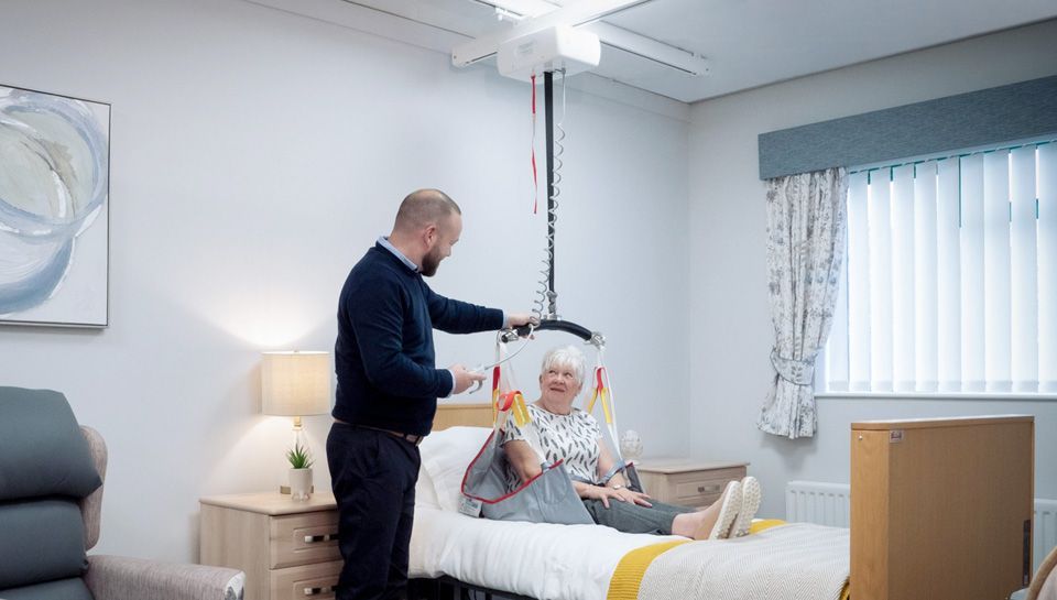 Ceiling lift track system installed above a bed in a home bedroom