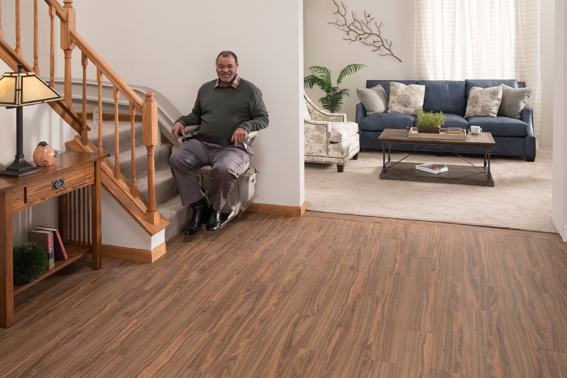 A man in a wheelchair sitting on a stairlift in a living room, from Altamira Ltd.