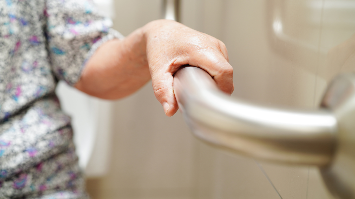 A woman is holding onto a grab bar after Altamira Ltd. installed it in a bathroom.