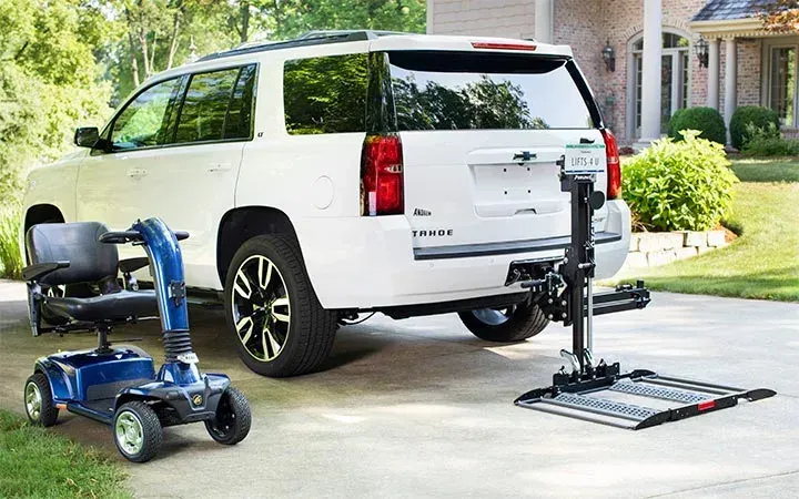 A Bruno Out-Sider exterior vehicle lift carrying a mobility scooter on a hitch-mounted platform