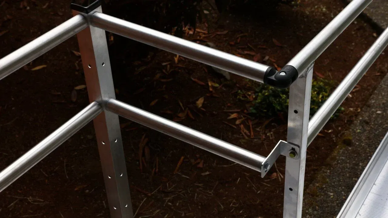 A close up of a metal ramp railing with a black handle