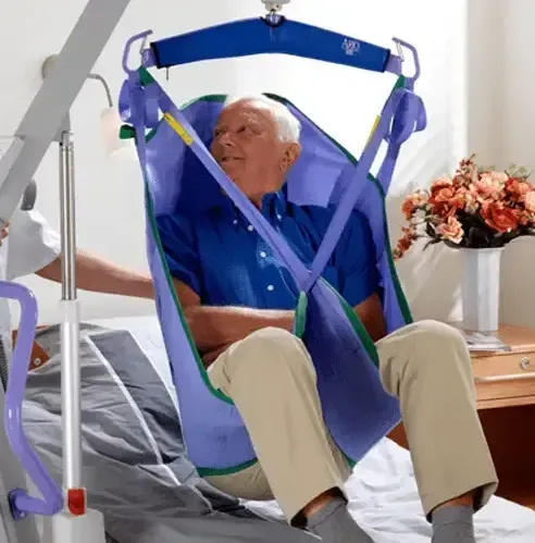A caregiver assisting a patient with a sling-style patient lift