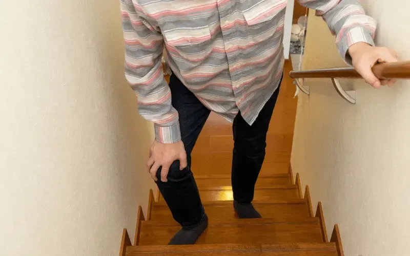 Person pausing partway up a staircase to rest