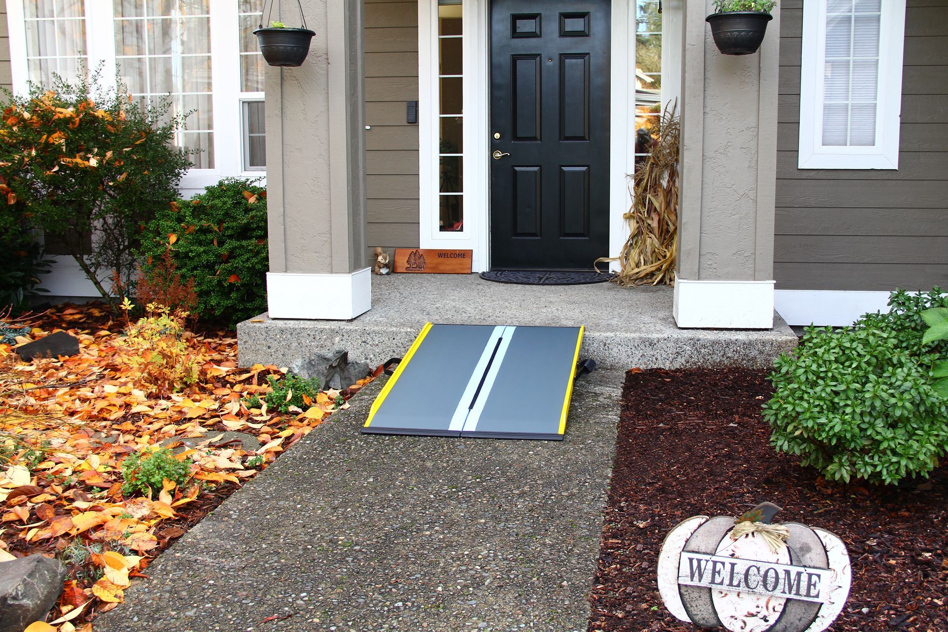 A welcome sign on the sidewalk in front of a house with a ramp