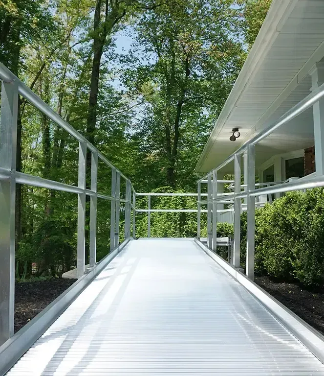 An aluminum wheelchair ramp with handrails leading to a New Jersey home, installed by Altamira Ltd.