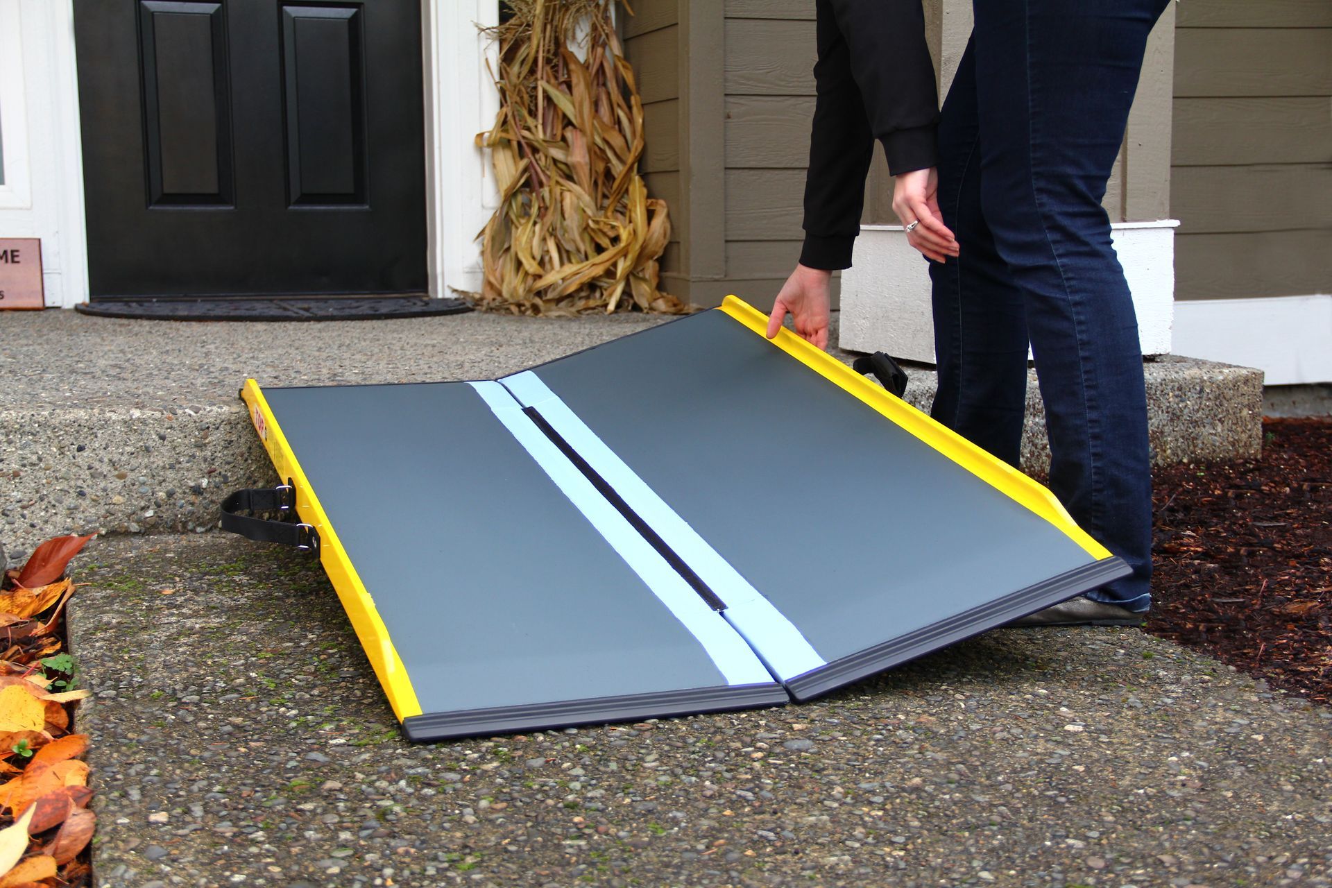 A person standing next to a portable folding wheelchair ramp, from Altamira Ltd.