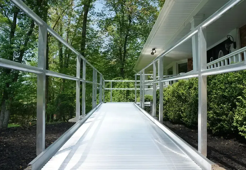 An Altamira Ltd. wheelchair ramp leading to a house with trees in the background.