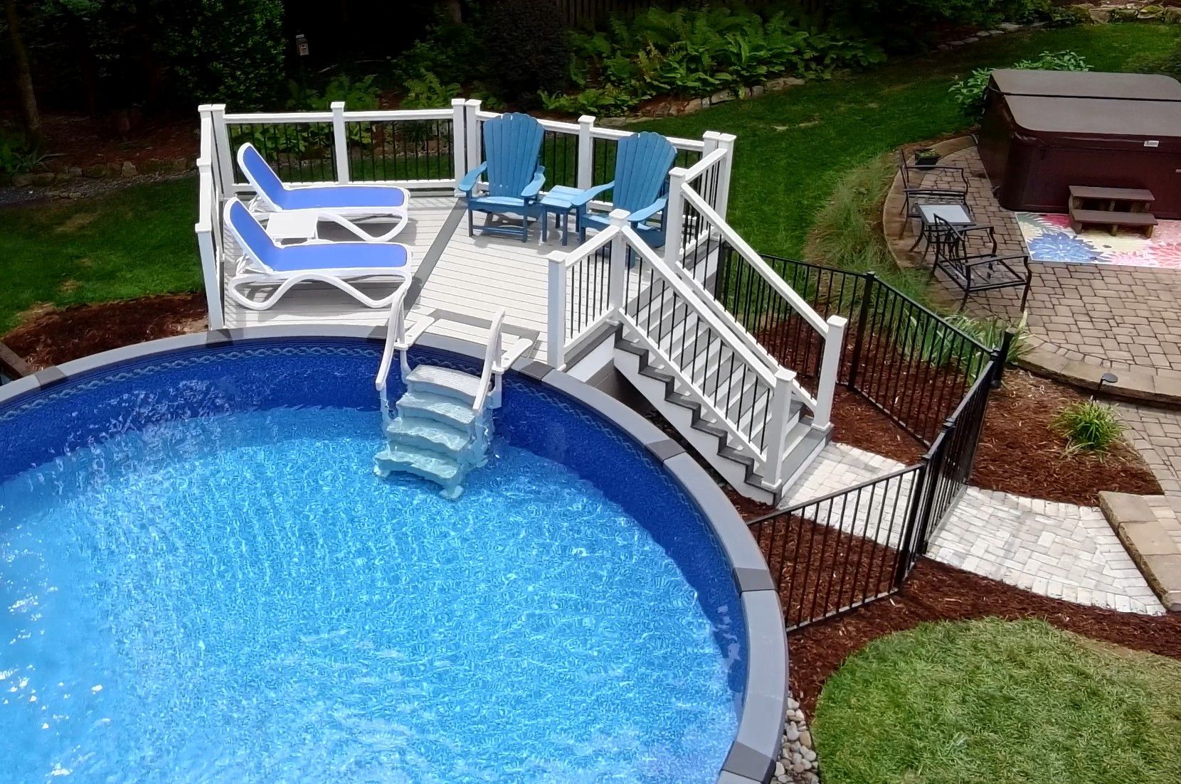 Backyard pool with white steps, blue lounge chairs, and a small bridge over the water