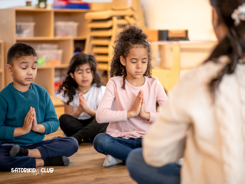 A group of children are sitting on the floor in a classroom, meditating.| Satori Kid Club