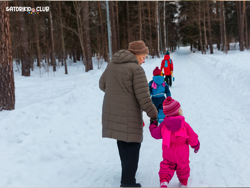 A woman holds a child's hand while going on a Nature Noticing Walk Meditation in the snow.| Satori Kid Club