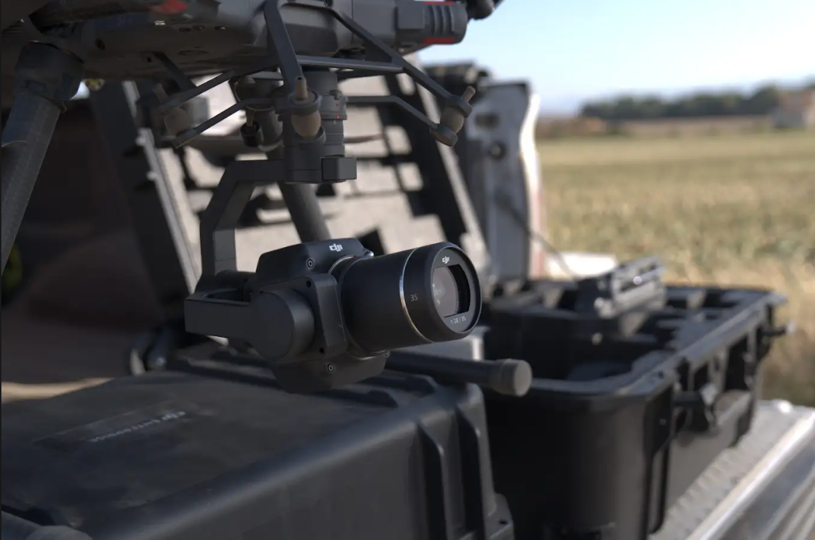 A drone is sitting on top of a case in a field.